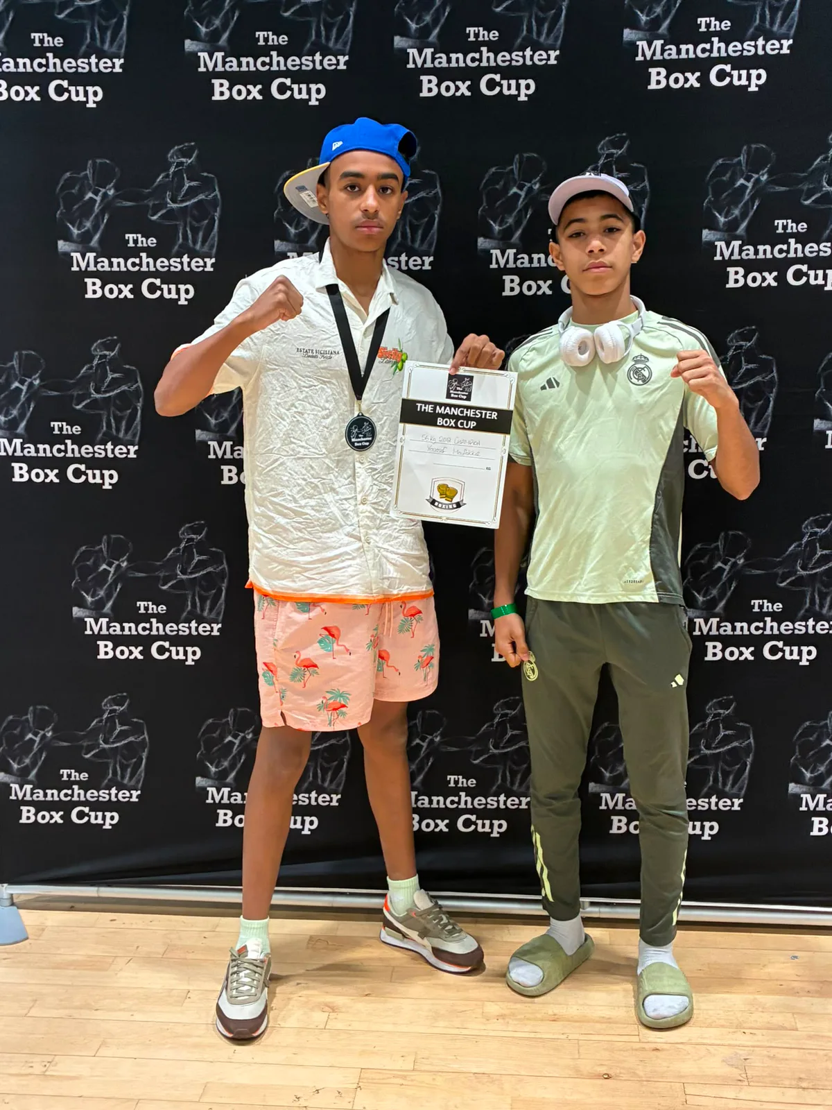 Two young boxers holding a Manchester Box Cup certificate and medal
